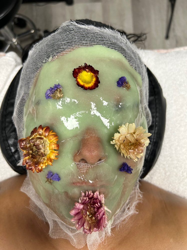 Client resting under a green hydro-jelly mask set with dried flowers