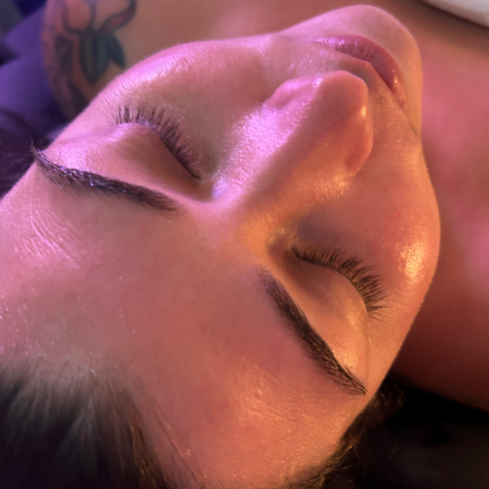 Client relaxing under warm treatment lighting during a radiofrequency facial