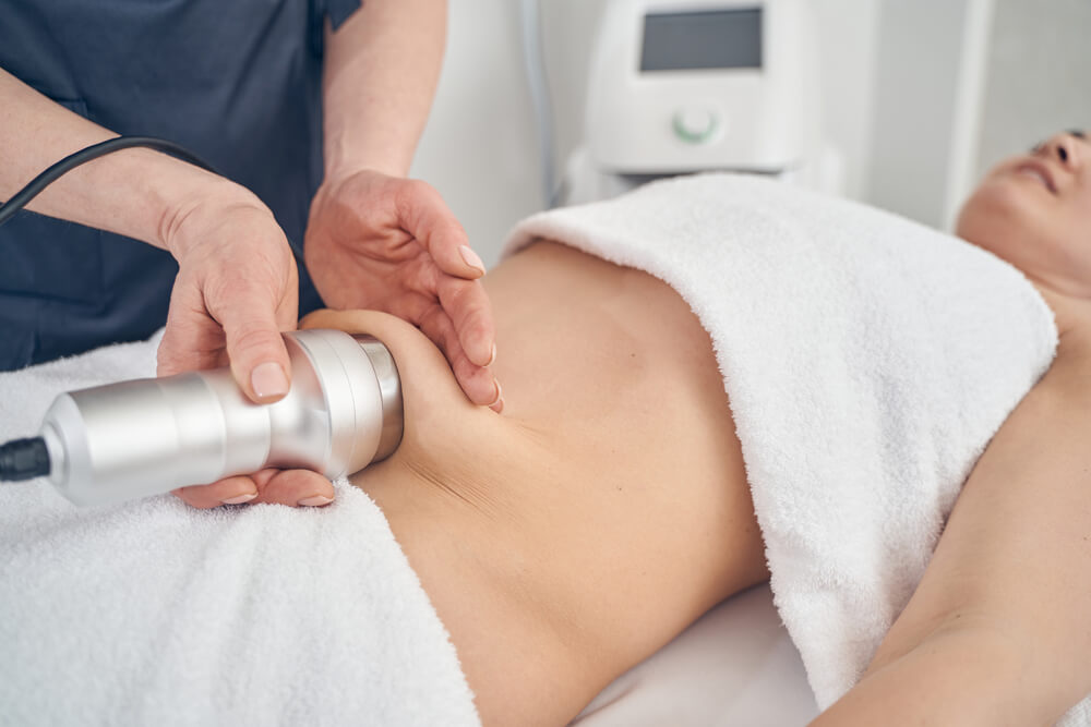 Ultrasound cavitation head being moved across a client's abdomen